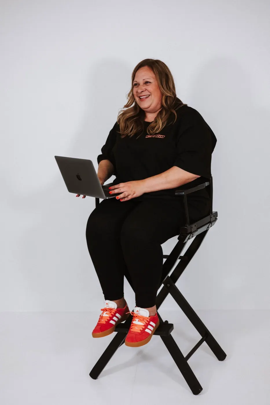 Jo sitting on a director's chair, working on her laptop.